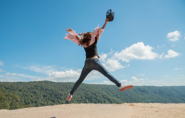 Junge Frau, die am Bergblick für Sonnenlicht springt