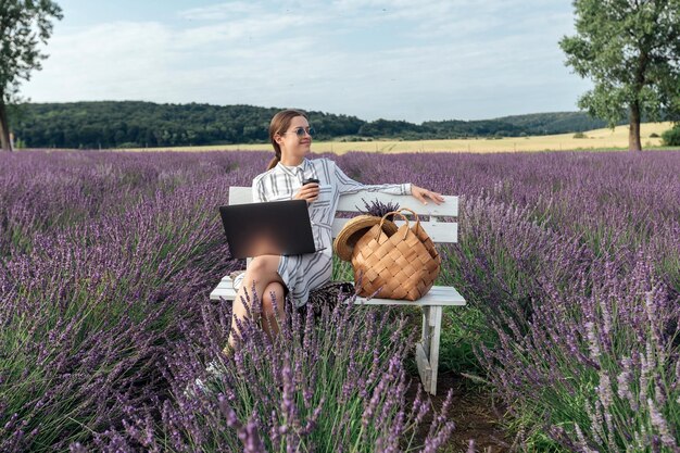 Junge Frau, die am Computer auf dem Lavendelgebiet arbeitet