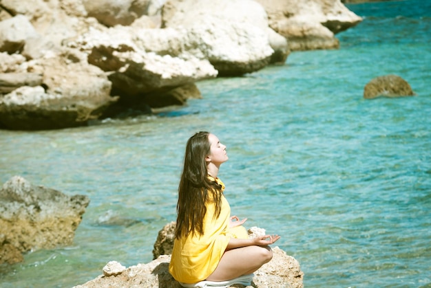 Junge Frau, die am Meereshintergrund meditiert