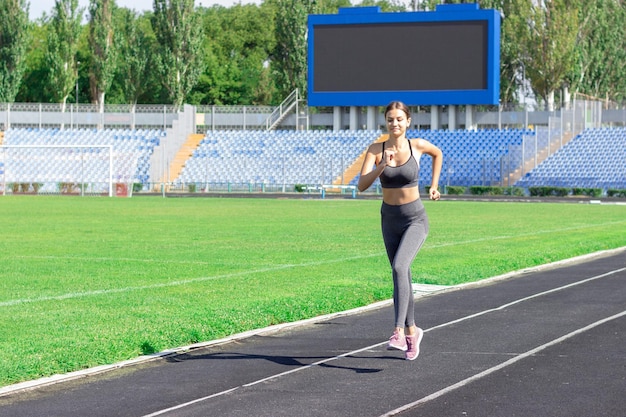 Junge Frau, die am sonnigen Morgen auf der Stadionstrecke läuft Menschen Sport- und Fitnesskonzept