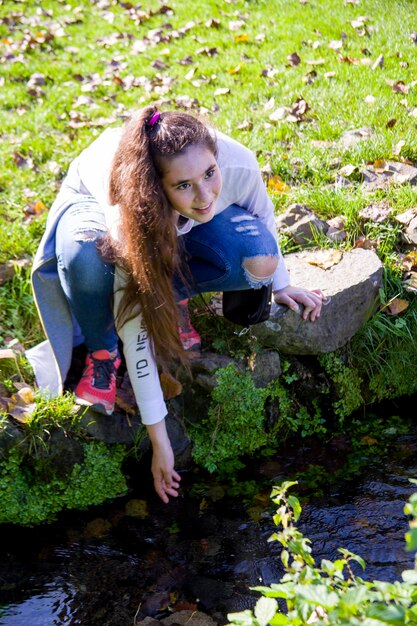 Foto junge frau, die am teich hockt