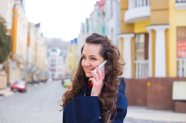 Junge Frau, die am Telefon, Smartphone auf der Straße spricht.