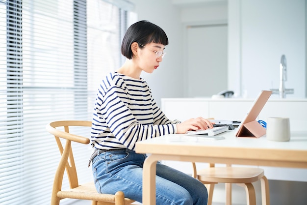 Junge Frau, die am Tisch im Zimmer arbeitet