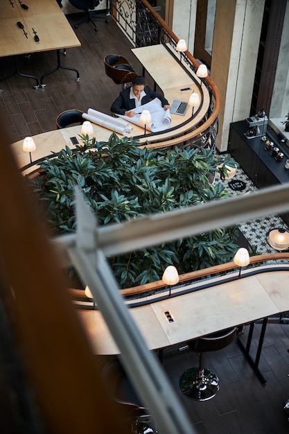 Foto junge frau, die am tisch sitzt, während sie an ihrem projekt im flex-office arbeitet