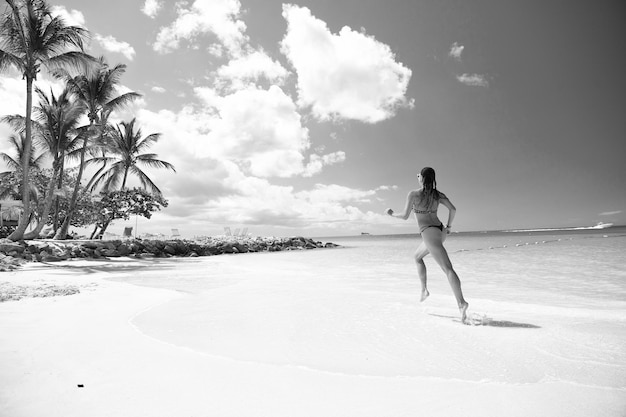 Junge Frau, die am tropischen Strand läuft