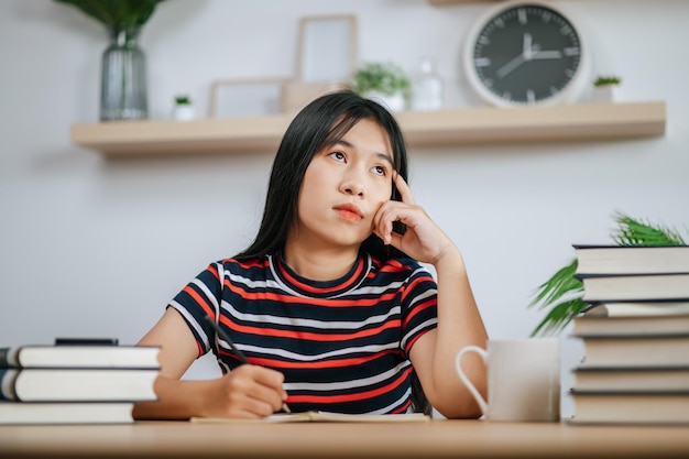 Junge Frau, die an einem Buch auf dem Tisch arbeitet und Stress hat