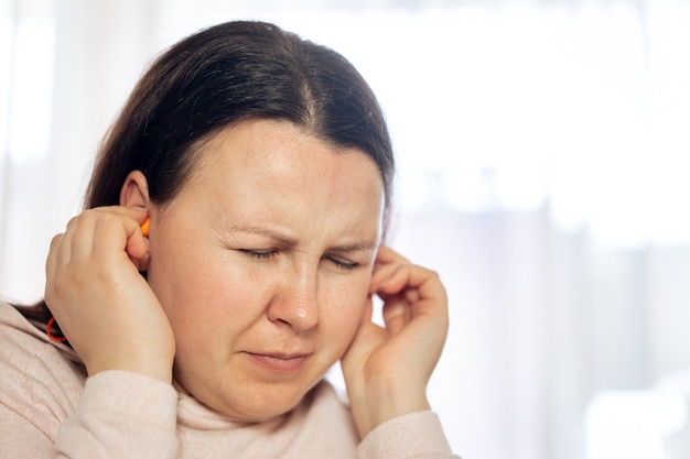 Junge Frau, die an einer Tinnitus-Krankheit des Zivilisationsgesundheitskonzepts leidet