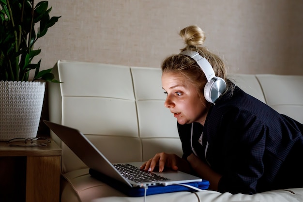 Junge Frau, die an Laptop-Computer arbeitet, während sie im Wohnzimmer sitzt.