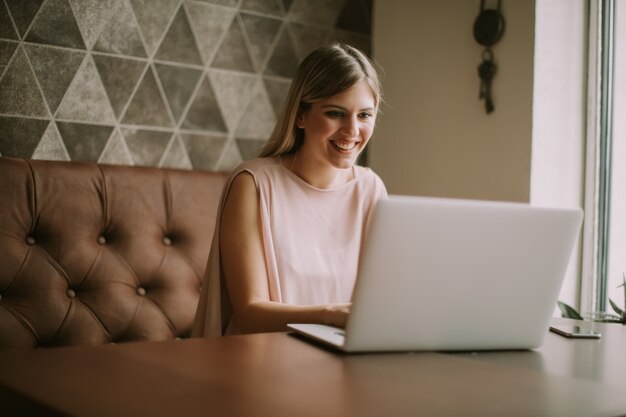 Junge Frau, die an Laptop im Café arbeitet