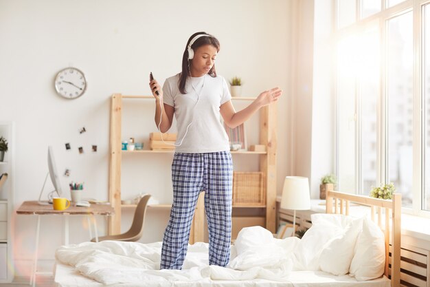 Junge Frau, die auf Bett tanzt