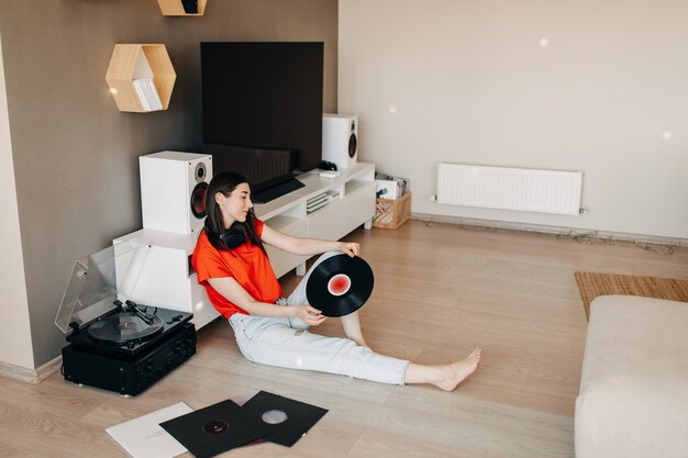 Junge Frau, die auf dem Boden liegt und Musik auf einem Vinyl-Spieler hört