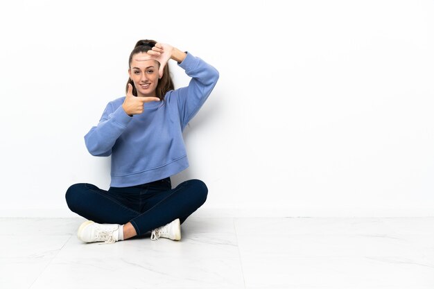 Junge Frau, die auf dem Fokusgesicht des Bodens sitzt. Rahmensymbol