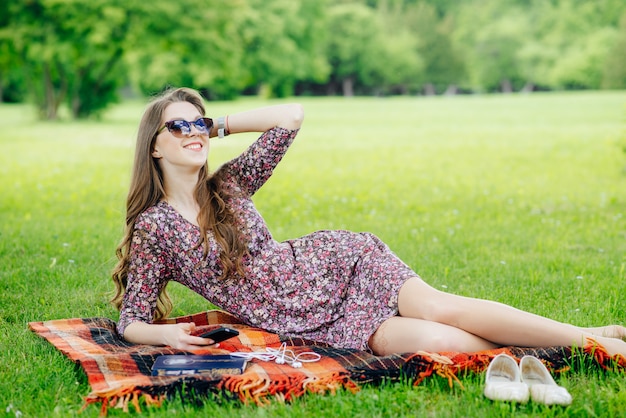 Junge Frau, die auf dem Gras am Park entspannt