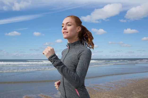 Junge Frau, die auf den Strand läuft