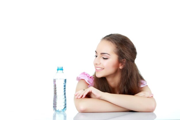 Junge Frau, die auf der Flasche Wasser auf weißem Hintergrund schaut