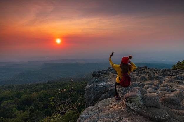 Foto junge frau, die auf einem felsen in den bergen sitzt