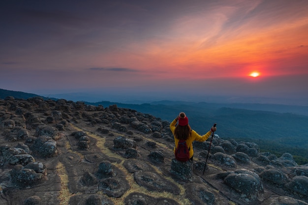 Junge Frau, die auf einem Felsen in den Bergen sitzt