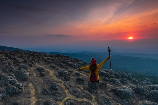 Junge Frau, die auf einem Felsen in den Bergen sitzt