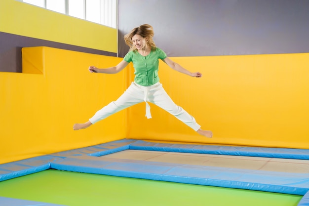 Junge Frau, die auf einem Trampolin im Sportzentrum springt und hüpft