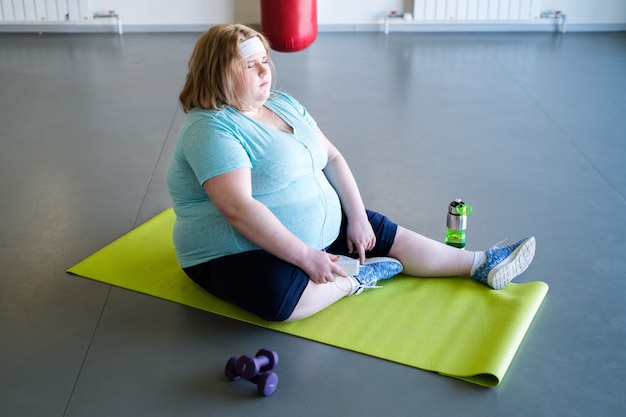 Junge Frau, die auf einer Fitnessmatte ruht