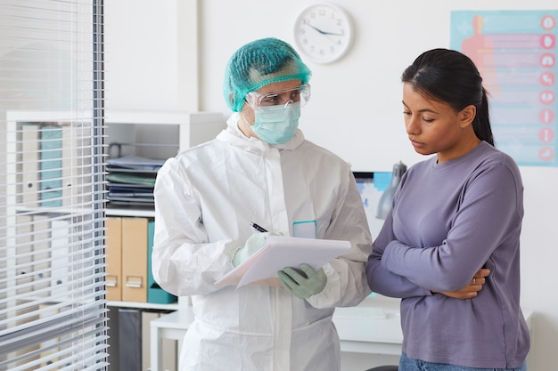 Junge Frau, die auf Empfehlung des Arztes hört, während er ihr ein Medikament im Krankenhaus verschreibt