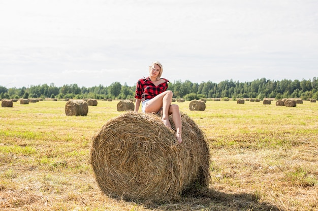 Junge Frau, die auf Heuballen sitzt. Hochwertiges Foto