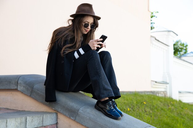 Junge Frau, die auf ihrem Telefon tippt. Streetstyle