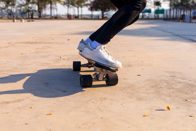 Junge Frau, die auf Seitenstraße nahe tropischem Strand mit Skateboard geht.