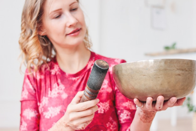 Junge Frau, die auf tibetanischer Messingklangschale spielt. Klangtherapie und Meditation