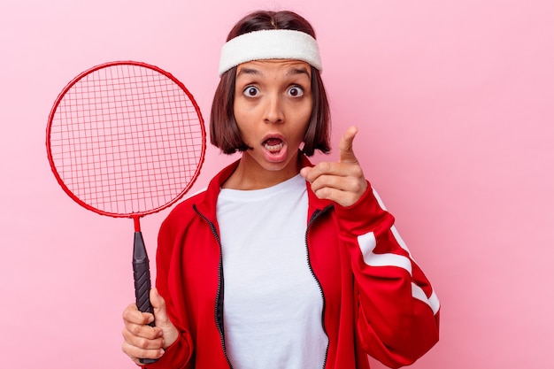 Junge Frau, die Badminton spielt, isoliert auf rosa Wand, die eine Idee hat