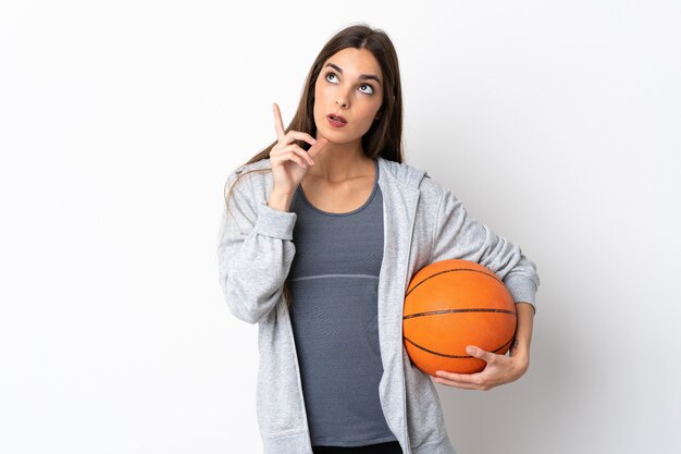 Junge Frau, die Basketball auf Weiß spielt und eine Idee denkt, die den Finger nach oben zeigt