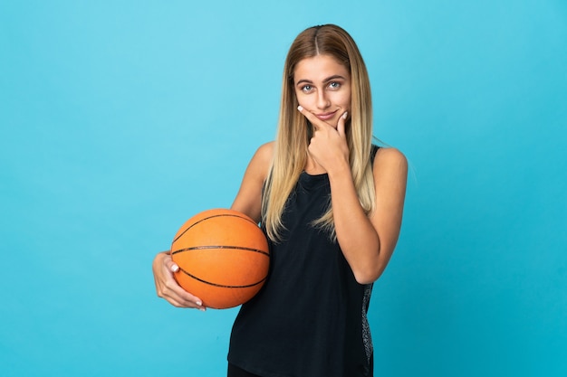 Junge Frau, die Basketball lokalisiert auf weißem Hintergrund denkt