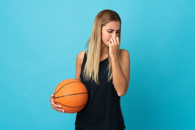 Junge Frau, die Basketball lokalisiert auf weißer Wand spielt, die Zweifel hat