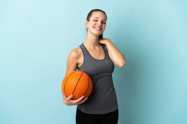 Junge Frau, die Basketball spielt, der auf lachendem blauen Wand lokalisiert wird