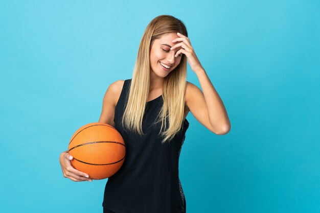 Junge Frau, die Basketball spielt, der auf lachendem Weißraum lokalisiert wird