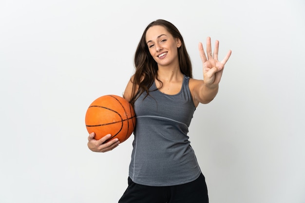 Junge Frau, die Basketball über isolierte weiße Wand glücklich spielt und vier mit den Fingern zählt