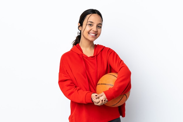 Junge Frau, die Basketball über isoliertem weißem Lachen spielt