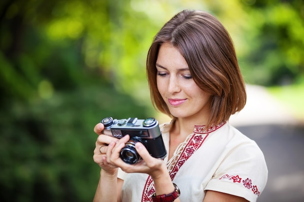 Foto junge frau, die bildschirm der retroartkamera betrachtet und lächelt