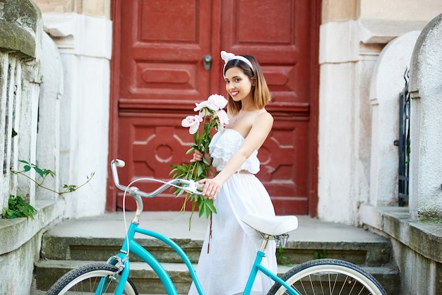 Junge Frau, die blaues Stadtfahrrad im Freien reitet