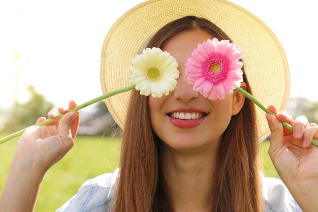 Junge Frau, die Blumen auf ihren Augen hält