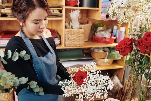 Junge Frau, die Blumen im Blumenstrauß anordnet