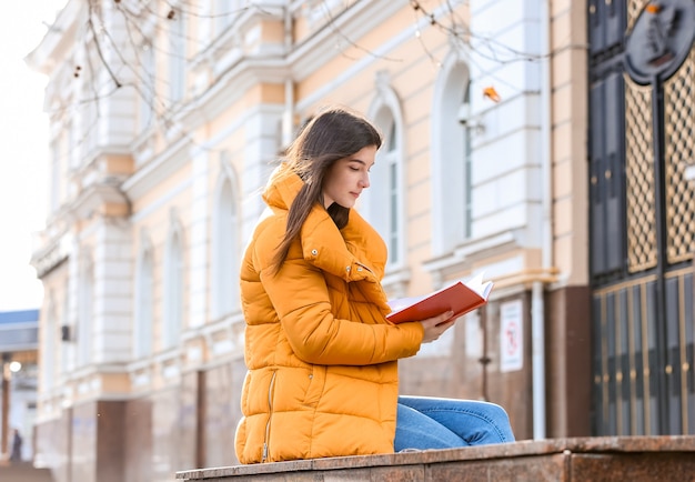 Junge Frau, die Buch draußen liest