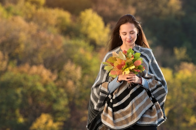 Junge Frau, die Bündel Herbstblätter hält