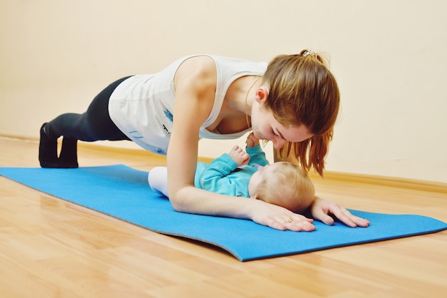 Junge Frau, die Übungen mit Baby macht