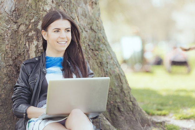 Junge Frau, die Computer am Park in London verwendet