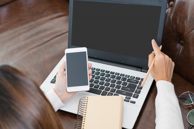 Junge Frau, die Computer benutzt, der zu Hause arbeitet.