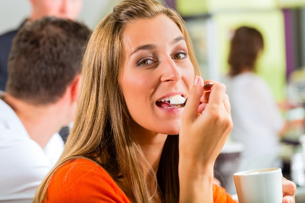 Junge Frau, die Creme im Café isst