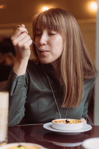 Junge Frau, die cremiges Brlée-Dessert im Café genießt, das köstliche karamellisierte Katalonien-Crema probiert