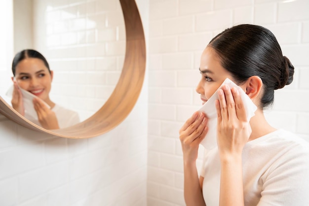 Junge Frau, die das Make-up auf ihrem Gesicht im Badezimmer zu Hause entfernt Schönheits-Wellness-Konzept