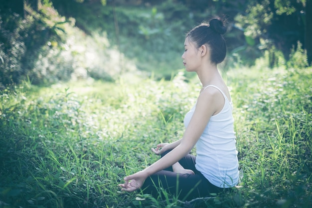 Junge Frau, die das Yogatraining im Freien in einem Nebenfluss tut